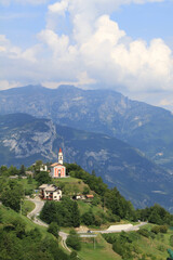 Fototapeta na wymiar Mountain landscape with a small red church in Guardia, Trentino, Italy