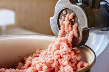 Minced meat coming out of a metal grinder