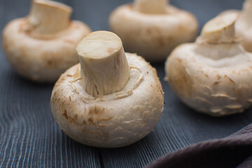 Fresh champignon mushrooms lie on a gray wooden table.