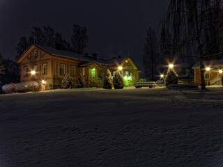 Fototapeta premium Beautiful wooden house in the winter evening in the snow with illumination.