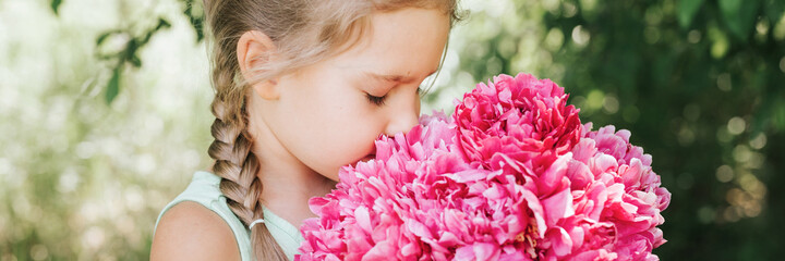 portrait of a happy cute little caucasian seven year old kid girl, holds in hands and smell and...