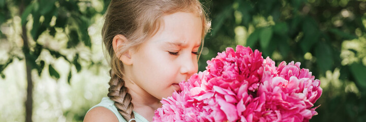 portrait of a happy cute little caucasian seven year old kid girl, holds in hands and smell and...