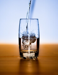 Frisches Wasser wird in ein Glas voller Wasser geschüttet.