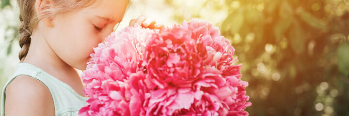 portrait of a happy cute little caucasian seven year old kid girl, holds in hands and smell and...