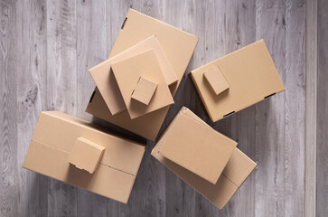 Stack of cardboard box on floor laminate background. Cardboard boxes for moving to new home - obrazy, fototapety, plakaty
