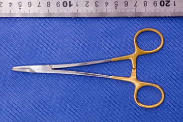 mayo needle holder with tungsten carbide blades on a blue background