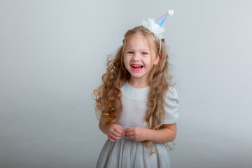 little girl in a birthday cap celebrates her birthday on a white background