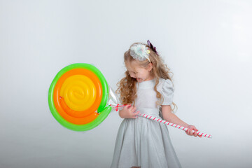 little girl in a birthday hat with a lollipop on a white background studio
