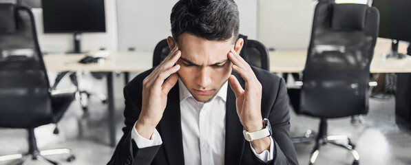Stressed businessman having problems at work. Tired overworked man having headache during the hard...