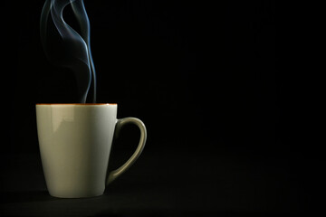 A steaming gray cup of coffee on black background, place for text