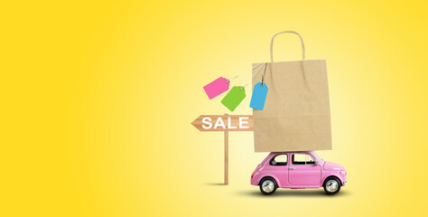 Pink car with shopping paper bag on the roof. Sale concept