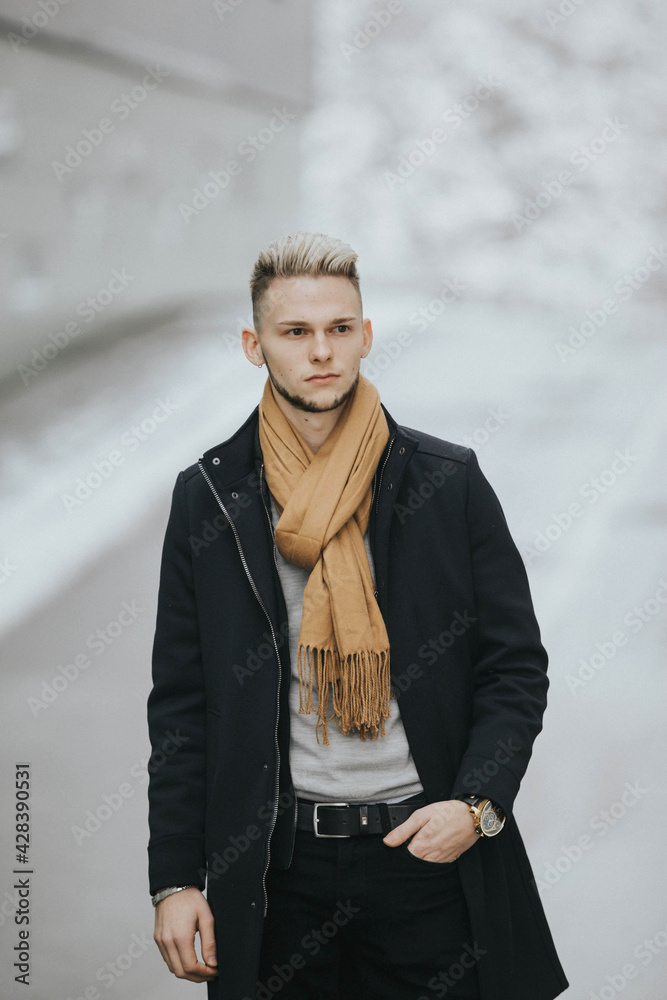 Wall mural Vertical shot of a caucasian stylish male posing outdoors in a snowy city