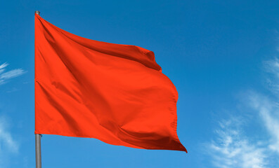 Bright red flag waving against blue sky, blank red banner - 428392199