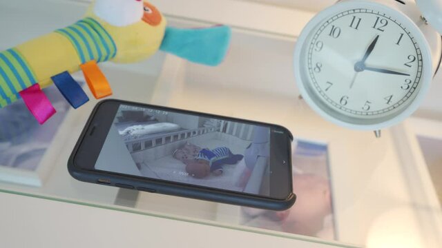 Video baby monitor app on phone, on smartphone screen newborn infant sleeping in crib. High quality 4k footage