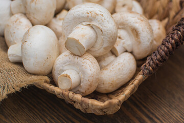 Fresh champignons in a wicker basket on a dark wooden background.