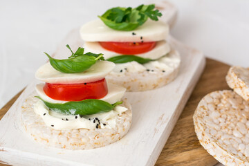 Rice cake sandwich with cheese cream, mozzarella, tomato, basil and spices. A healthy dietary snack