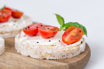 Rice cake sandwich with cheese cream, tomato, basil and spices. A healthy dietary snack