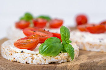 Rice cake sandwich with cheese cream, tomato, basil and spices. A healthy dietary snack