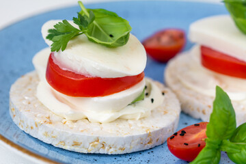 Rice cake sandwich with cheese cream, mozzarella, tomato, basil and spices. A healthy dietary snack