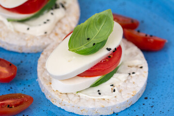 Rice cake sandwich with cheese cream, mozzarella, tomato, basil and spices. A healthy dietary snack