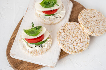 Rice cake sandwich with cheese cream, mozzarella, tomato, basil and spices. A healthy dietary snack