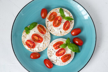 Rice cake sandwich with cheese cream, tomato, basil and spices. A healthy dietary snack