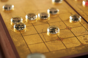 glass pieces of chinese chess on the gold colored chess board