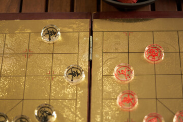 glass pieces of chinese chess on the gold colored chess board