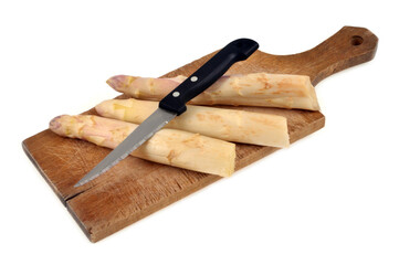 Asperges crues avec un couteau sur une planche à découper en gros plan sur fond blanc