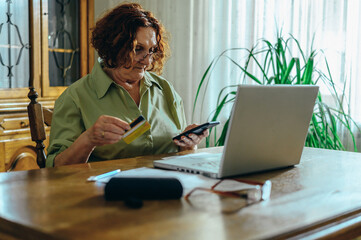 Senior woman using a smartphone and laptop at home