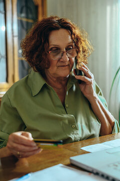 Senior woman using a smartphone and holding a credit card at home
