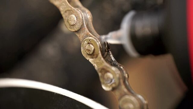 Close-up of oiling the links of a bicycle chain with fine oil, care of the bike after winter