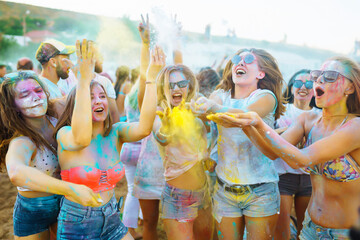 Group of people have fun at the holi festival of colors. Smiling faces in colorful powder....