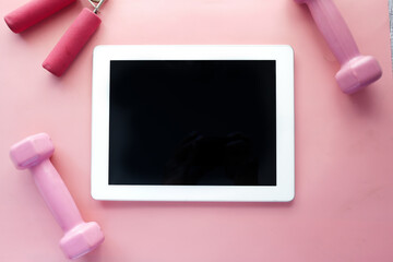  digital tablet with sports equipment on pink background 