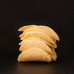 Stack of potato chips on a black background.  Crispy potato chips. Salty snack