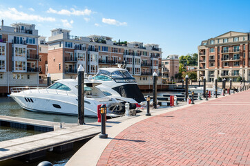 Yachts moored to jetties in a marina surrounded by modern apartment buildings on a sunny autumn...