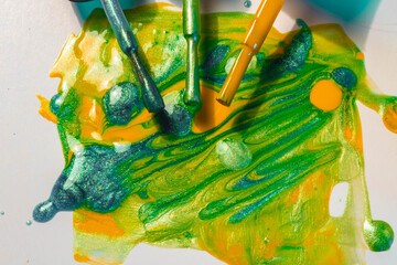 Bright nail polish in green, yellow, blue colors with sparkles spilled