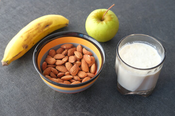  almond nut , banana, apple and milk on table 