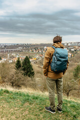 Man with backpack enjoying view of Prokopske valley nature reserve and residential district,Prague,Czech Republic.Attractive landscape with deep valleys,limestone rocks,hiking trails.Active lifestyle