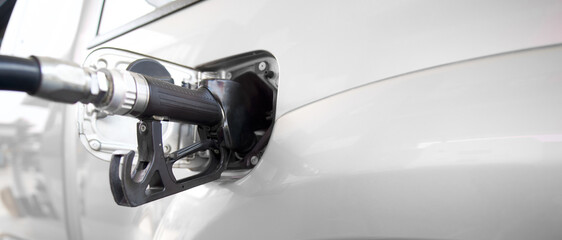 Black diesel gas pump nozzle filling up bronze pickup truck tank. Close up © chadchai