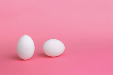 White eggs on a pink background. The concept of minimalism. Side view. A card with a copy of the place for the text.