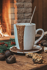 Cozy scene near fireplace with mug of hot drink, nuts and cookies .