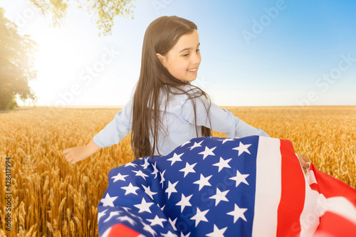 American flag. Little patriotic happy girl running with american flag waving on nature outdoor background. USA celebrate 4th of July.