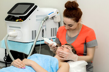A beautiful girl takes the procedure of ultrasonic facial cleaning in a beauty salon.