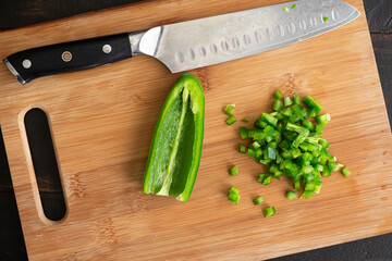 Minced Jalapeño Pepper on a Cutting Board: Minced green chili pepper on a wooden chopping board