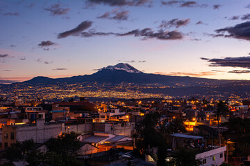 Fototapeta premium Chimborazo Volcano next to a beautiful city at a beatiful sunset