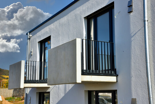 Moderner Balkon mit Sichtschutz aus Milchglasplatten an einer Neubau-Hausfront