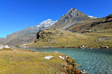 Naklejka premium lake in a valley in alpine national Park in France with mountain peak background
