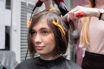 Fototapeta premium Hairdressing salon. Hairdresser girl doing hairstyle to a young woman