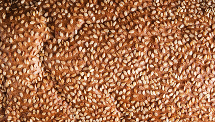 Crust of ruddy fresh bread sprinkled with sesame seeds.